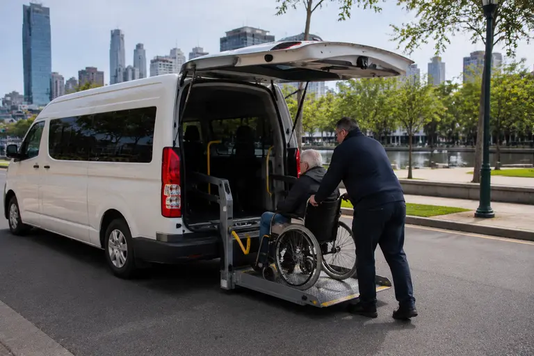Wheelchair accessible taxi Melbourne, driver assisting a passenger up the ramp into a Maxi Taxi van